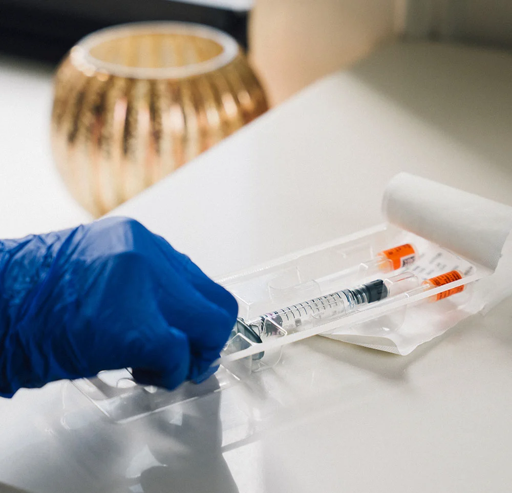 A persons hand in medical blue glove grabbing a syringe from it's package - Non-surgical Facelift in Toronto, ON